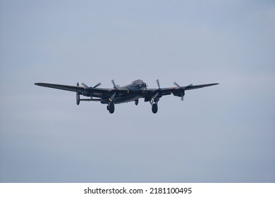 A World War II bomber flying with the landing gear down