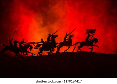 World war officer (or warrior) rider on horse with a sword ready to fight and soldiers on a dark foggy toned background. Battle scene battlefield of fighting soldiers. Selective focus