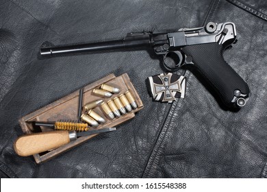 World War I period german army handgun Parabellum "Artillery Luger" with ammuniotion and accessories on black leather jacket background