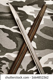 World War Two era rifle bayonet detail on camouflage fabric