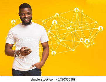 Worldwide Connection Technology Interface. Happy Black Man Holding Cell Phone With Icons And Hologram, Yellow Background