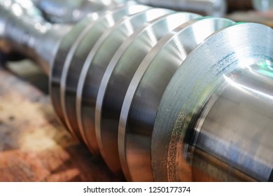 The worm shaft after machining lies on a wooden rack and is ready for use in mechanical engineering and metallurgy. Photo threaded coils close-up.