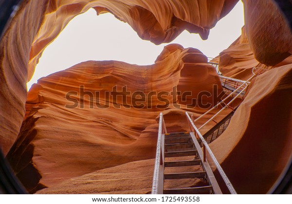 Worm\'s eye view\
of beautiful Lower Antelope canyon. A spectacular orange sandstone\
cave with white sky and metal stair at the entrance. Natural\
landscape in Page, Arizona,\
USA