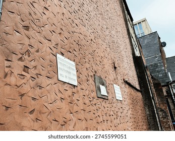 Worn brick wall and graffiti create an edgy urban mood in Manchester, UK.