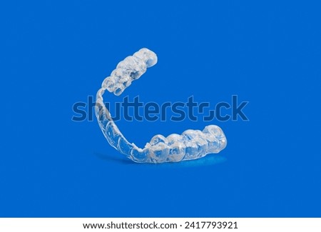 Worn and broken invisible orthodontic removable braces on blue background with copy space.Aligners for straightening of teeth