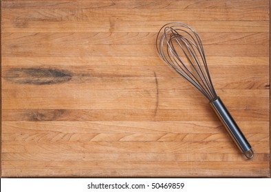 A worn butcher block cutting board sits as a background with a wire whisk to one side.