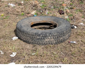 A Worn Car Tire Is Wallowing In Mud And A Puddle On The Ground. Environmental Pollution. Ecological Problems.