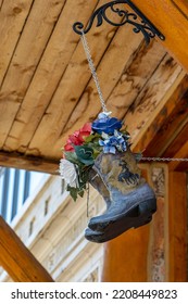 Worn Cowboy Boots Hang From A Ceiling Filled With Red, White And Blue Flowers.  Boots Have The Wyoming Symbol Of Bucking Bronco With Rider On Them,