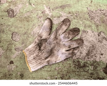 A worn, dirty glove on a rough surface, symbolizing industrial safety and personal protective equipment (PPE) in challenging work environments - Powered by Shutterstock