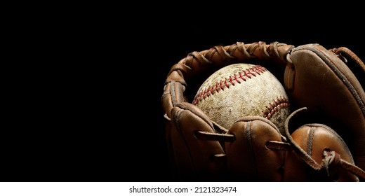 Worn old baseball in brown leather mitt or glove - Shutterstock ID 2121323474