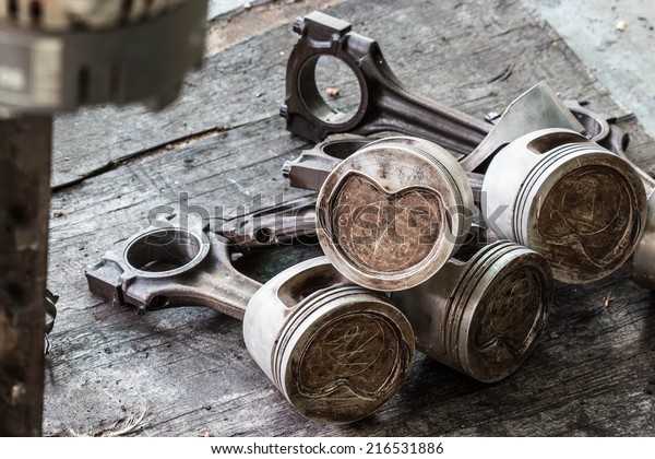 Worn out piston and\
connecting rod, dismantled from the internal combustion engine on\
wood background