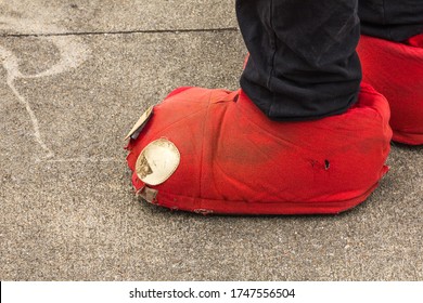 Worn Out Red Clown Shoes On Pavement