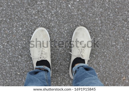 Worn out skateboard shoes, jeans and socks on asphalt background