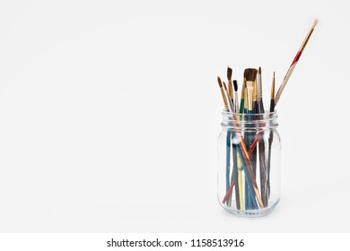 Worn paintbrushes in a glass jar - Powered by Shutterstock