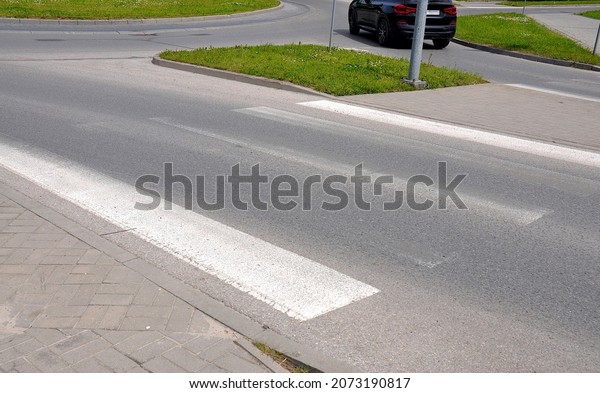 Worn pedestrian\
crossing lanes on the road