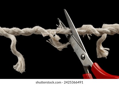 Worn rope ready to break, with scissors on black background