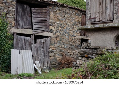 Worn Stone Storage Shed & Grain Storage In Rural Galicia, Spain On A Grey Day With Metal Sheets Covering Doorway. 
