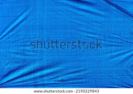 Worn tarpaulin material as background, blue weathered tarp texture