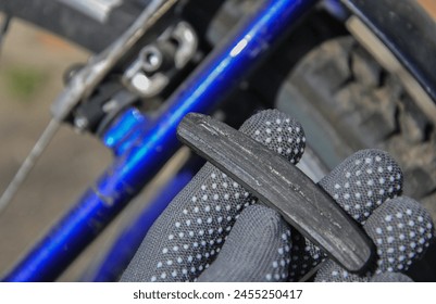 worn V-Brake bicycle brake pads. worn bicycle brake pad in the gloved hand of a master. bicycle brake system repair. bike service - Powered by Shutterstock