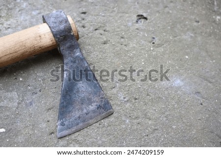 The wornout axe head rests on aged concrete, revealing its weathered look and history of use