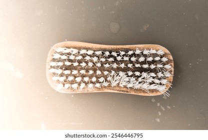 A worn-out cleaning brush with frayed bristles lies flat against a smooth surface, showing signs of long-term use and wear. - Powered by Shutterstock