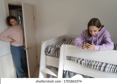 Worried Adult Parent Mom Coming To Teenage Child Bedroom Unhappy About Technology Addicted Kid Using Phone, Obsessed With Mobile Social Media Apps. Teens Gadgets Overuse And Parental Control Concept.