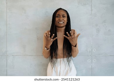 Worried African American businesswoman gestures , wearing formal attire, standing against the minimalist backdrop of a contemporary office space. - Powered by Shutterstock