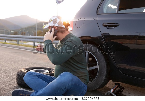 a worried and angry driver on the phone calling for\
help on the road