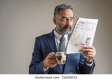 Worried And Anxious Senior Business Man Looking At The Newspaper With Shock And Terror On His Face