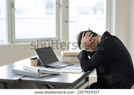 Worried asian businessman holding his head