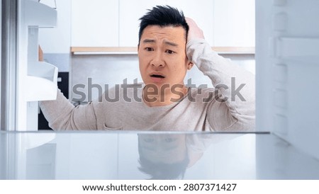 Worried Asian Man Checking Empty Fridge At Home, Kitchen Situation, Food Wastage Concept