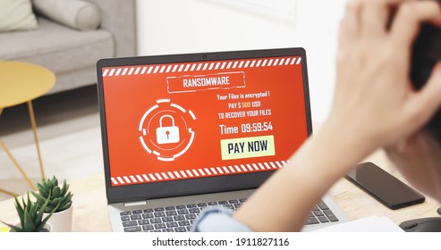 worried asian young woman looking at laptop computer with ransomware attack words on the screen at home