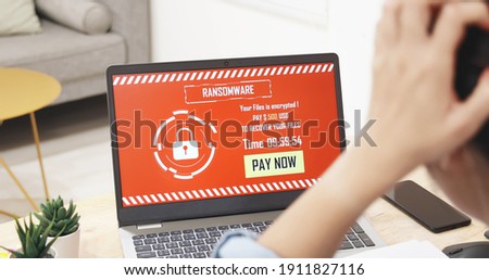worried asian young woman looking at laptop computer with ransomware attack words on the screen at home