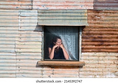 A Worried Australian Farmer Wife Looking Out Of A Window In The Outback Of Western Australia.