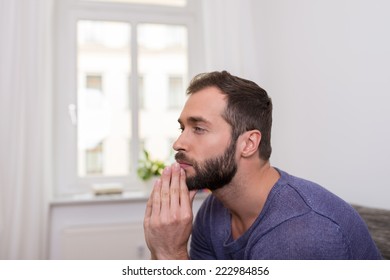 Worried Bearded Man Sitting Thinking With His Clasped Hands To His Chin Staring Off Into Space In Contemplation