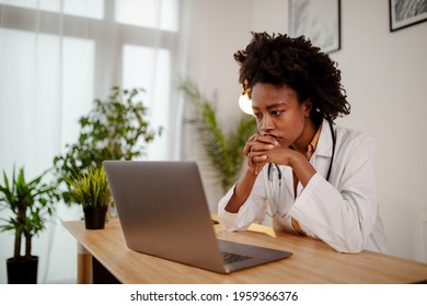 Worried black female doctor working on computer at her desk. - Powered by Shutterstock