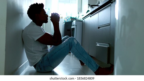 Worried black man sitting on floor feeling preoccupied, person with mental illness depressed