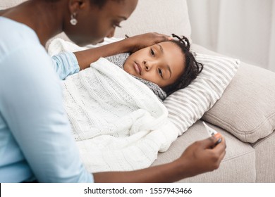 Worried Black Mom Measuring Temperature Of Her Sick Child At Home, Girl In Bed