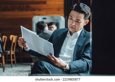 Worried Businessman Analyzing Documents While Sitting In Coffee Shop