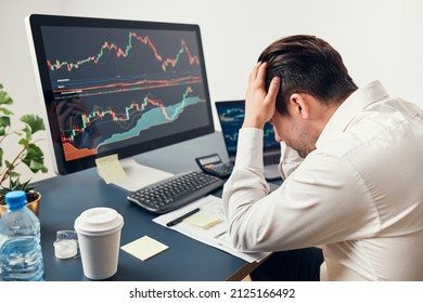 Worried businessman looking at charts stressed by news from stock market. Investor lost money online. Man analyses loss and profit. Businessman investing stocks online. Man working with stock charts