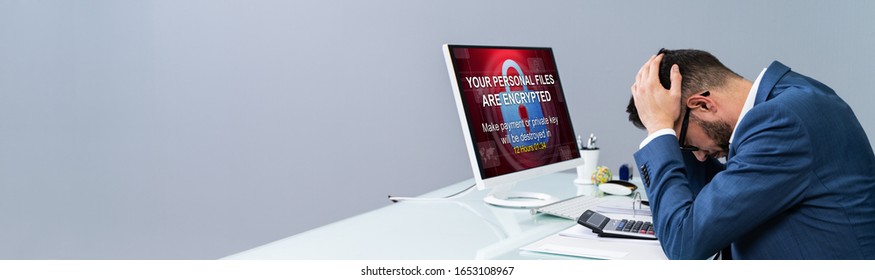 Worried Businessman Near Computer With Ransomware Word On The Screen At The Workplace