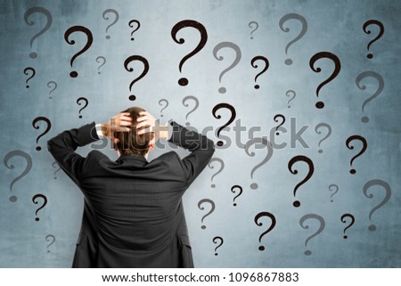 Worried businessman with question marks. Confusion and enquiry concept 