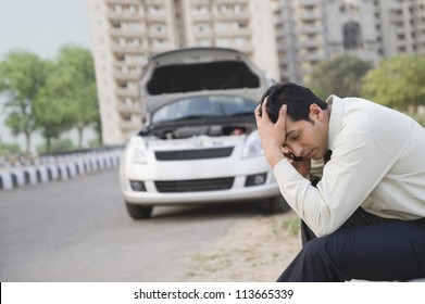 Worried Businessman Talking On A Mobile Phone After His Vehicle Breakdown