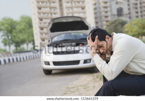 Worried businessman talking on a mobile phone\
after his vehicle\
breakdown