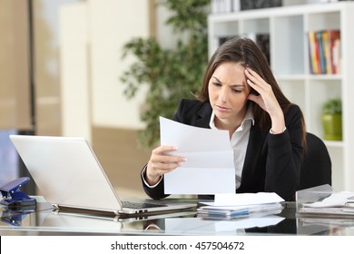 Worried businesswoman reading a notification sitting in a desktop at office - Powered by Shutterstock