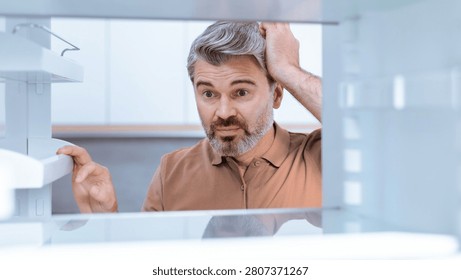 Worried Caucasian Man Checking Empty Refrigerator At Home, Weight Loss Concept