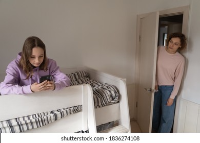 Worried Caucasian Mom Control 12s Teenage Daughter Using Smartphone Gadget. Anxious Mother Distressed With Small Teen Girl Child Kid Obsessed Addicted To Internet And Social Media, Cellphone Usage.