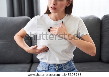 Worried caucasian woman carefully looking and checking breast by herself that she concern about breast cancer. Breast cancer concept