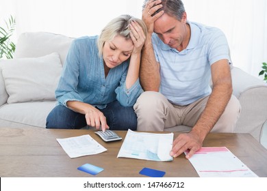 Worried Couple Going Over Finances At Home In Living Room