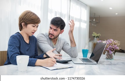 Worried Couple Pay Bills Online Via Laptop In Living Room. Young Man And Woman At Desk With Computer And Checkbook, Worrying About Expense Bills. Stressful Financial Married Problem Concept